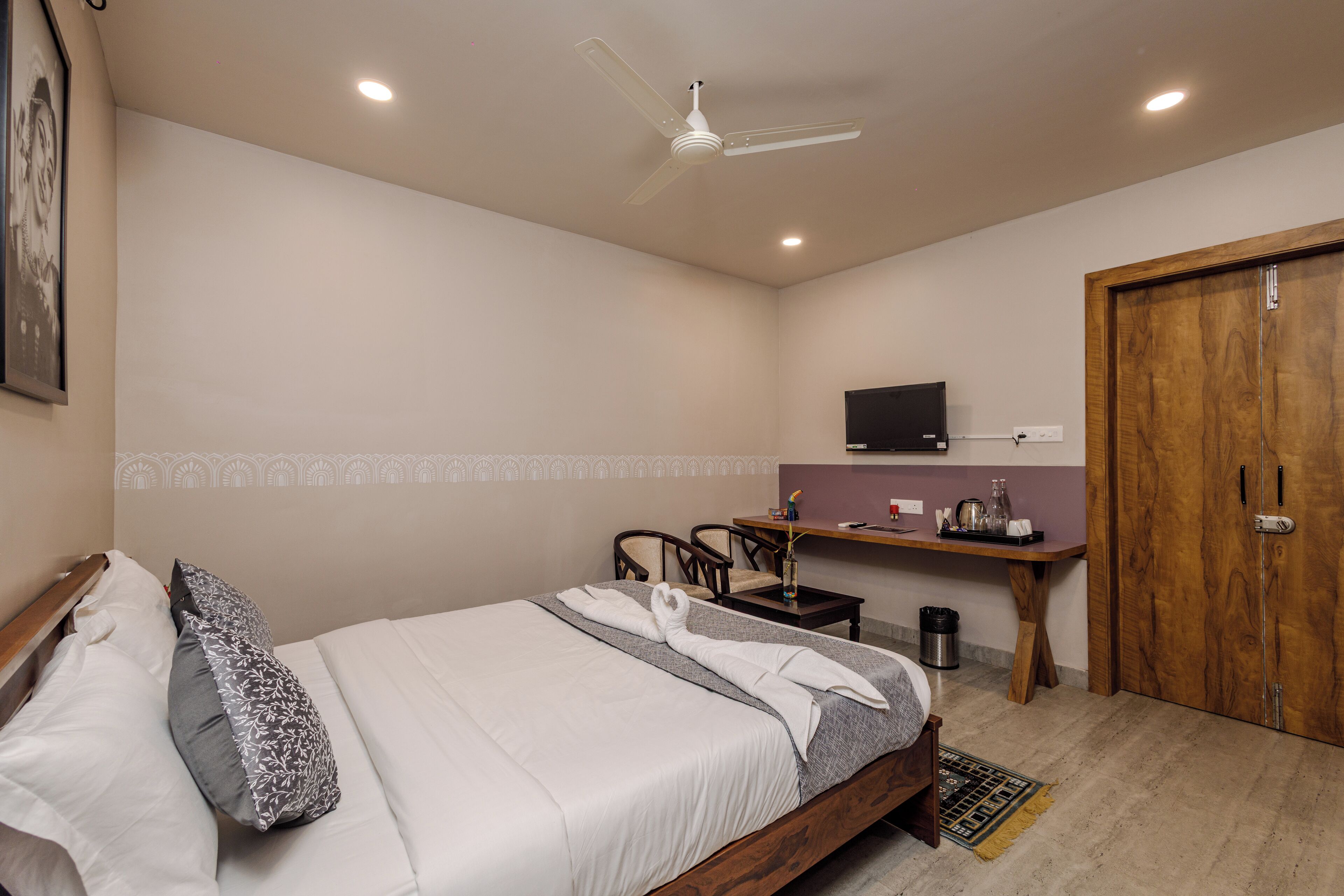 Una habitación de hotel con cama, escritorio, silla, televisor y armario.