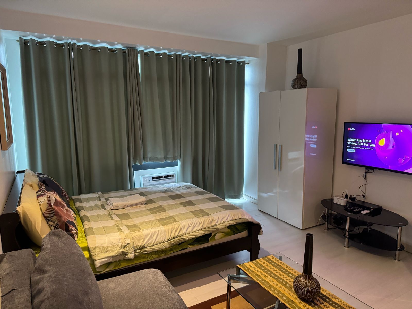 A modern bedroom with a bed, a TV, a wardrobe, and a small table.