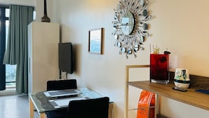 A modern dining area with a glass table, black chairs, a decorative wall clock, and a wooden shelf with items. - Makati City Poblacion (Makati)