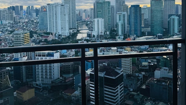 A cityscape viewed from a high-rise building with a river running through the center. - Makati City Poblacion (Makati)