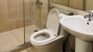 A modern bathroom with a glass-enclosed shower, a toilet, and a sink. - Makati City Poblacion (Makati)