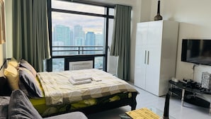 A modern bedroom with a bed, a sofa, a TV, and a wardrobe. - Makati City Poblacion (Makati)