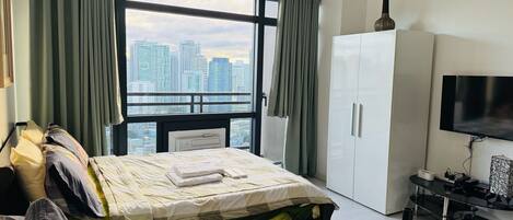 A modern bedroom with a bed, a sofa, a TV, and a wardrobe.