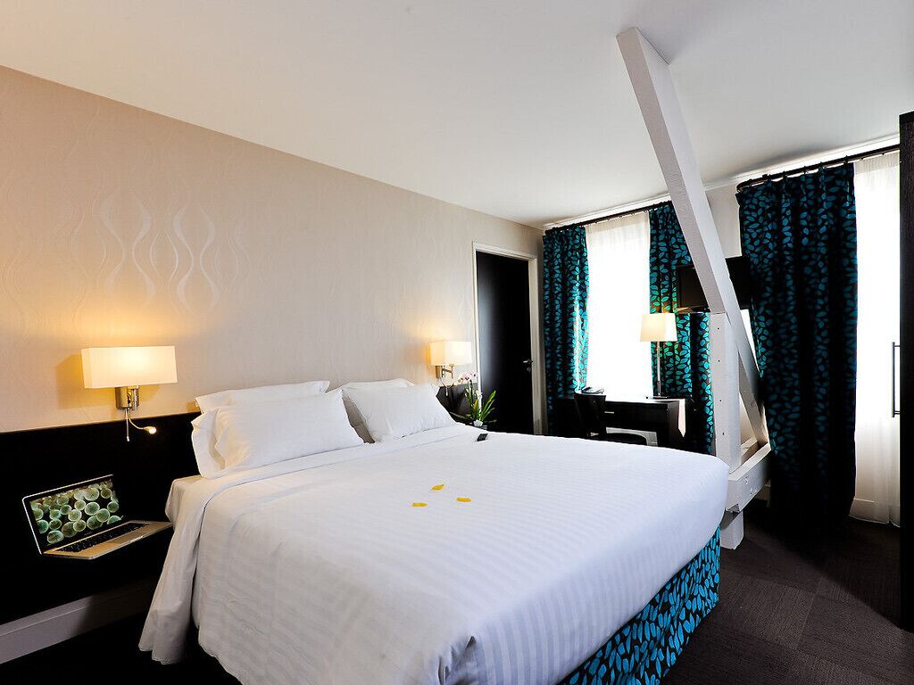 Una habitación de hotel con una cama grande, dos lámparas de noche, un escritorio y una silla.