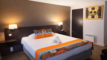 Ein Hotelzimmer mit einem großen Bett, zwei Nachttischlampen, einem Wandbild und einer sichtbaren Tür.