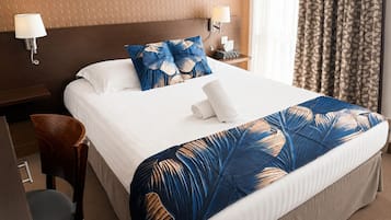 Una camera d'albergo con un letto grande, due lampade da comodino, un comodino in legno, una sedia e una tenda a motivi.