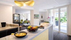 A modern kitchen with a fruit bowl, a coffee machine, and a unique pendant light. - Hôtel le saint pierre  (Mézidon Vallée d'Auge)