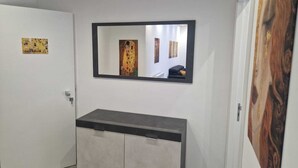 A hallway with a mirror, a gray cabinet, and a door. - KLIMT HOUSE. (Marsala)