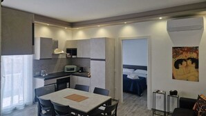 A compact hotel room with a kitchenette, a dining area, a bed, and a small sitting area. - KLIMT HOUSE. (Marsala)