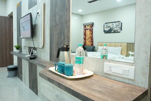 A hotel reception area with a wooden counter, a coffee machine, two blue mugs, and a water bottle. - RMV Inn (Katpadi)