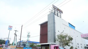 A building with a large sign for RMV Inn, a blue sign for KuMart, and a pink sign for AIR. - RMV Inn (Katpadi)