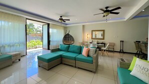 A spacious living area with a sectional sofa, a hanging chair, and a dining table with chairs. - Exceptional three-bedroom, two-and-a-half-bathroom ground floor condo (Playa Hermosa)