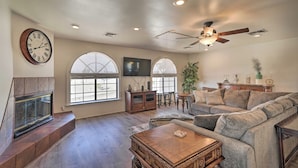 A spacious living room with a fireplace, a large sofa, a coffee table, and a ceiling fan. - Putting Green & Pool Table: Lake Havasu City Gem! (Lake Havasu City)