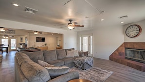 A spacious living room with a large sectional sofa, a fireplace, and a dining area in the background. - Putting Green & Pool Table: Lake Havasu City Gem! (Lake Havasu City)
