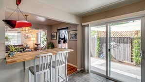 A kitchen with a wooden countertop, two white bar stools, a hanging red light fixture, and a sliding glass door leading to a backyard. - < 1 Mi to Oakland A's Park: West Sacramento Home (West Sacramento)