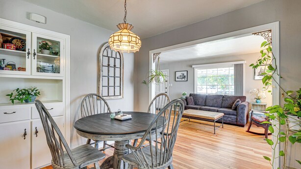 A dining area with a round table and chairs, a chandelier, and a view of a living room with a sofa and plants. - < 1 Mi to Oakland A's Park: West Sacramento Home (West Sacramento)
