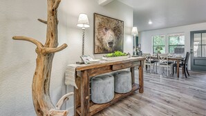 A dining area with a wooden table, chairs, and a large bear painting on the wall. - Mountain Retreat: Near Grindstone Lake & Trails! (Ruidoso)