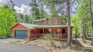 A two-story log cabin with a green metal roof, a covered porch, and a garage. - Mountain Retreat: Near Grindstone Lake & Trails! (Ruidoso)