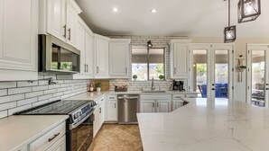 A modern kitchen with white cabinetry, a stainless steel dishwasher, and a large island. - Breathtaking Family Retreat in Elite Gold Canyon! (Gold Canyon)