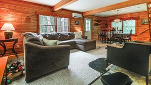 Een gezellig interieur van een chalet met een modulaire bank, een eettafel met stoelen en een open haard.