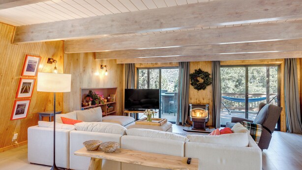 A cozy living room with a large sofa, a TV, and a fireplace. - Walk to Village: Cozy Cabin in Pine Mountain Club! (Pine Mountain Club)