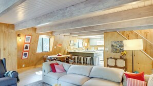 A spacious living area with a large sofa, a dining table, and a kitchen in the background. - Walk to Village: Cozy Cabin in Pine Mountain Club! (Pine Mountain Club)
