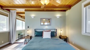A bedroom with a bed, a ceiling fan, a nightstand, a lamp, a mirror, and a window with curtains. - Boat Ramp + Dock: Waterfront Home on Clear Lake (Kelseyville)