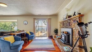A living room with a stone fireplace, a telescope, and a view through a glass door. - Boat Ramp + Dock: Waterfront Home on Clear Lake (Kelseyville)