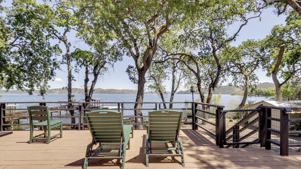 A wooden deck with green chairs and a railing overlooking a body of water. - Boat Ramp + Dock: Waterfront Home on Clear Lake (Kelseyville)