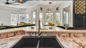 A modern kitchen with a large island, double sink, and pendant lighting.