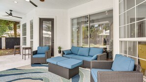 An outdoor patio area with wicker furniture, a patterned rug, and a ceiling fan.