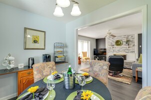 A dining area with a table set for two, a coffee station, and a television in the background.