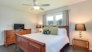 A bedroom with a bed, a TV, a dresser, and a ceiling fan.