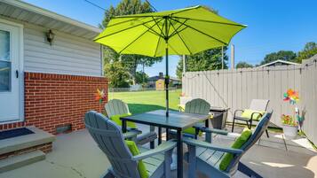 A patio with a table and chairs, an umbrella, and a fenced yard.