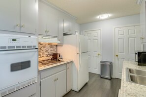 A kitchen with white cabinets, a built-in oven, a microwave, a toaster, and a stainless steel sink. - Charming Kingsport Home w/ Spacious Fenced Yard! (Kingsport)