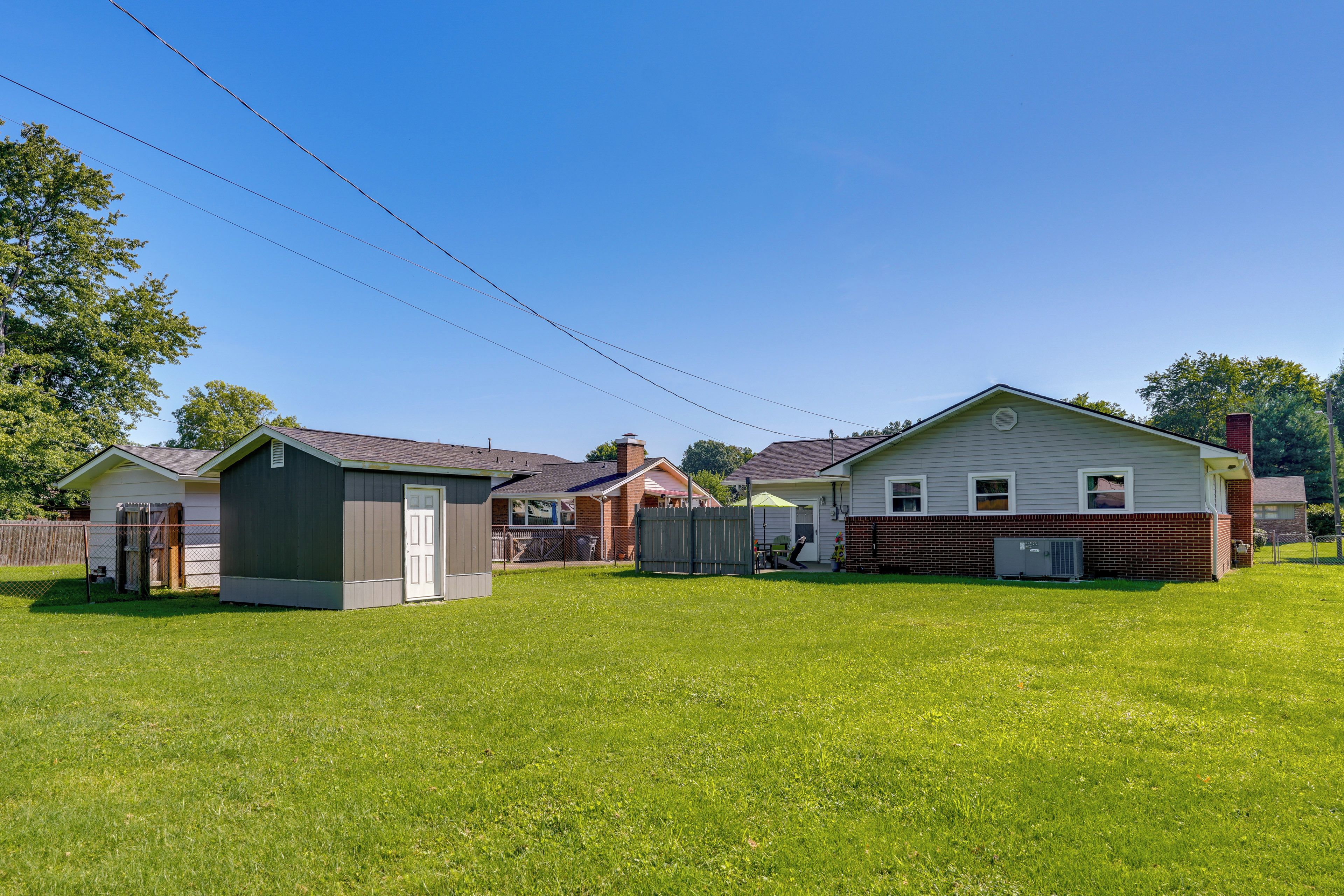 Una propiedad residencial con patio cercado, garaje y una casa con chimenea.