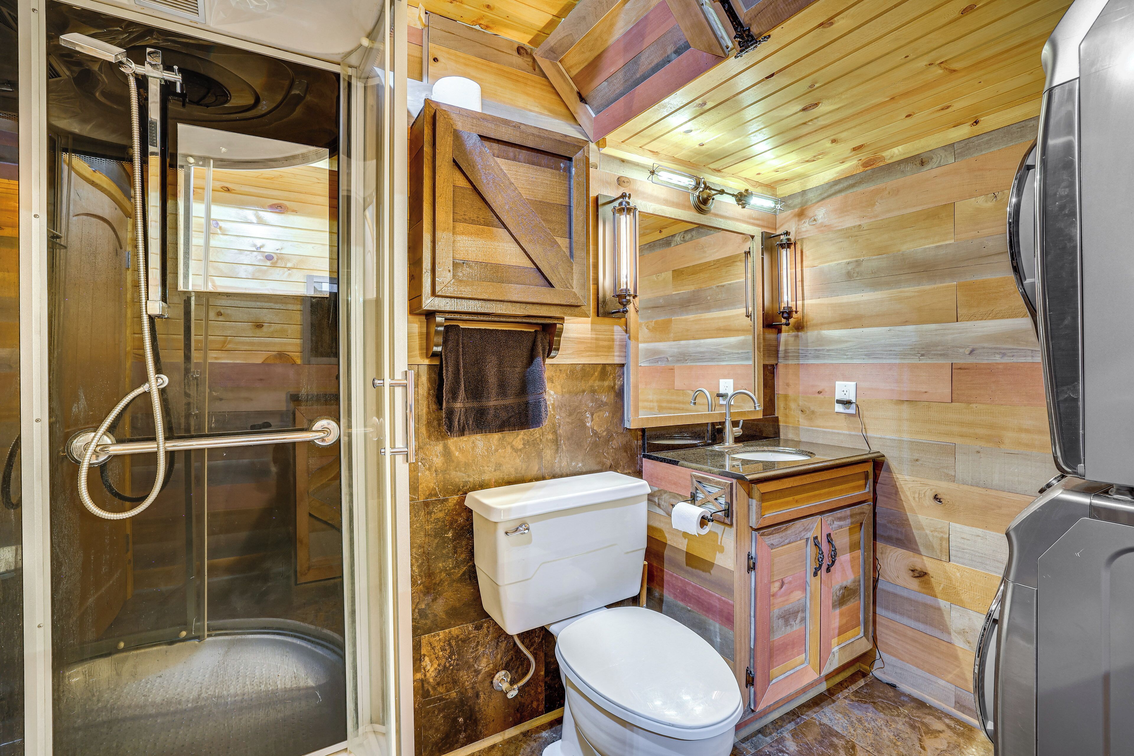 A compact bathroom with a shower, toilet, sink, and a mirror.