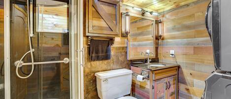 A compact bathroom with a shower, toilet, sink, and a mirror.