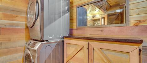 Ein kleiner Hauswirtschaftsraum mit Waschmaschine und Trockner, Holzwänden und einem Spiegelschrank.