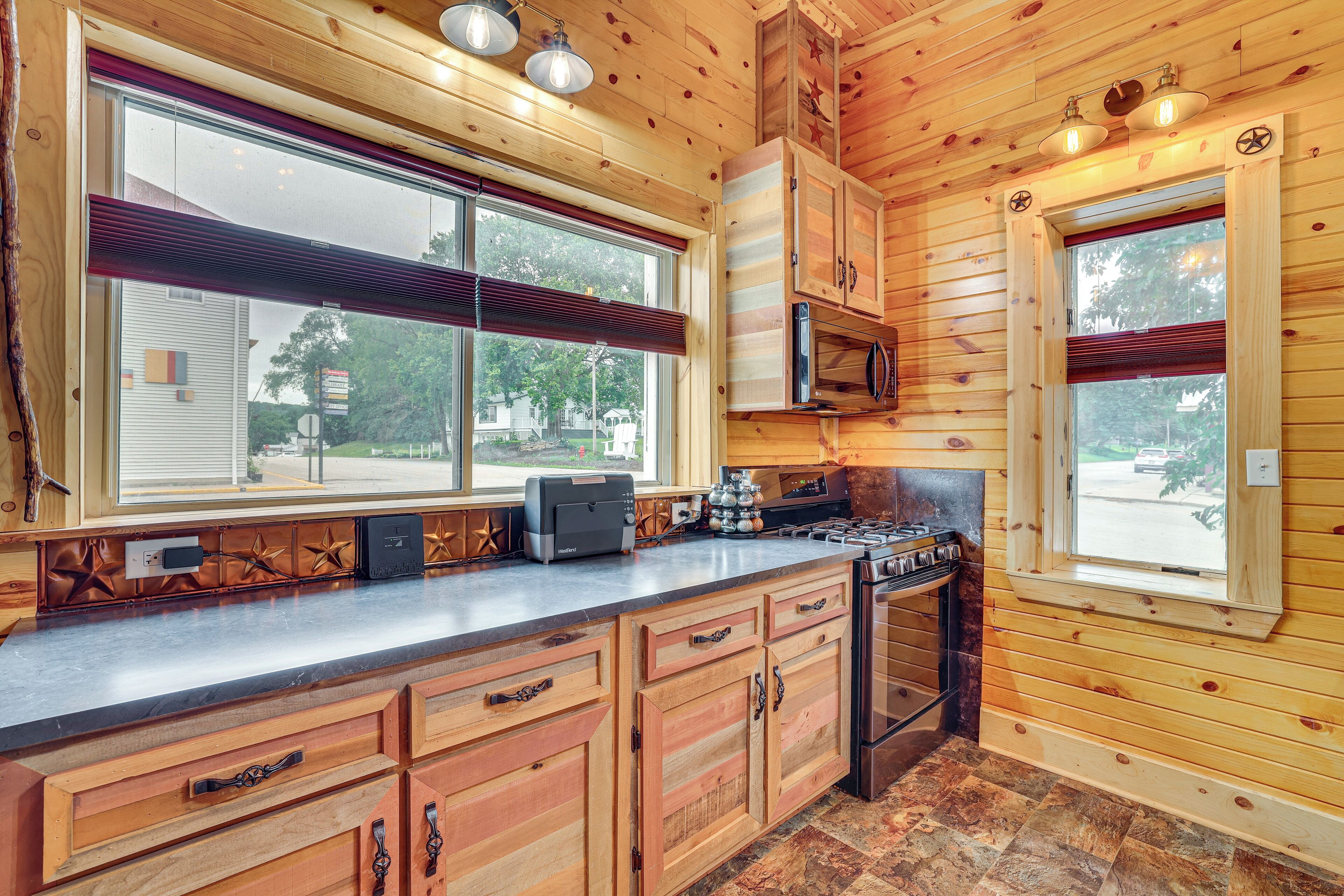 Cocina de cabaña de madera con una isla grande, microondas empotrado y estufa a gas.