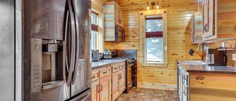Une cuisine moderne dotée d’appareils électroménagers en acier inoxydable, de meubles en bois et d’un revêtement de sol en carrelage de pierre.