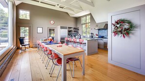 Een ruime keuken met moderne apparatuur, een eethoek met rode stoelen en een groot raam dat voor natuurlijk licht zorgt.