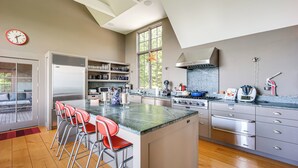 Een moderne keuken met een centraal eiland, roestvrijstalen apparatuur en een groot raam.