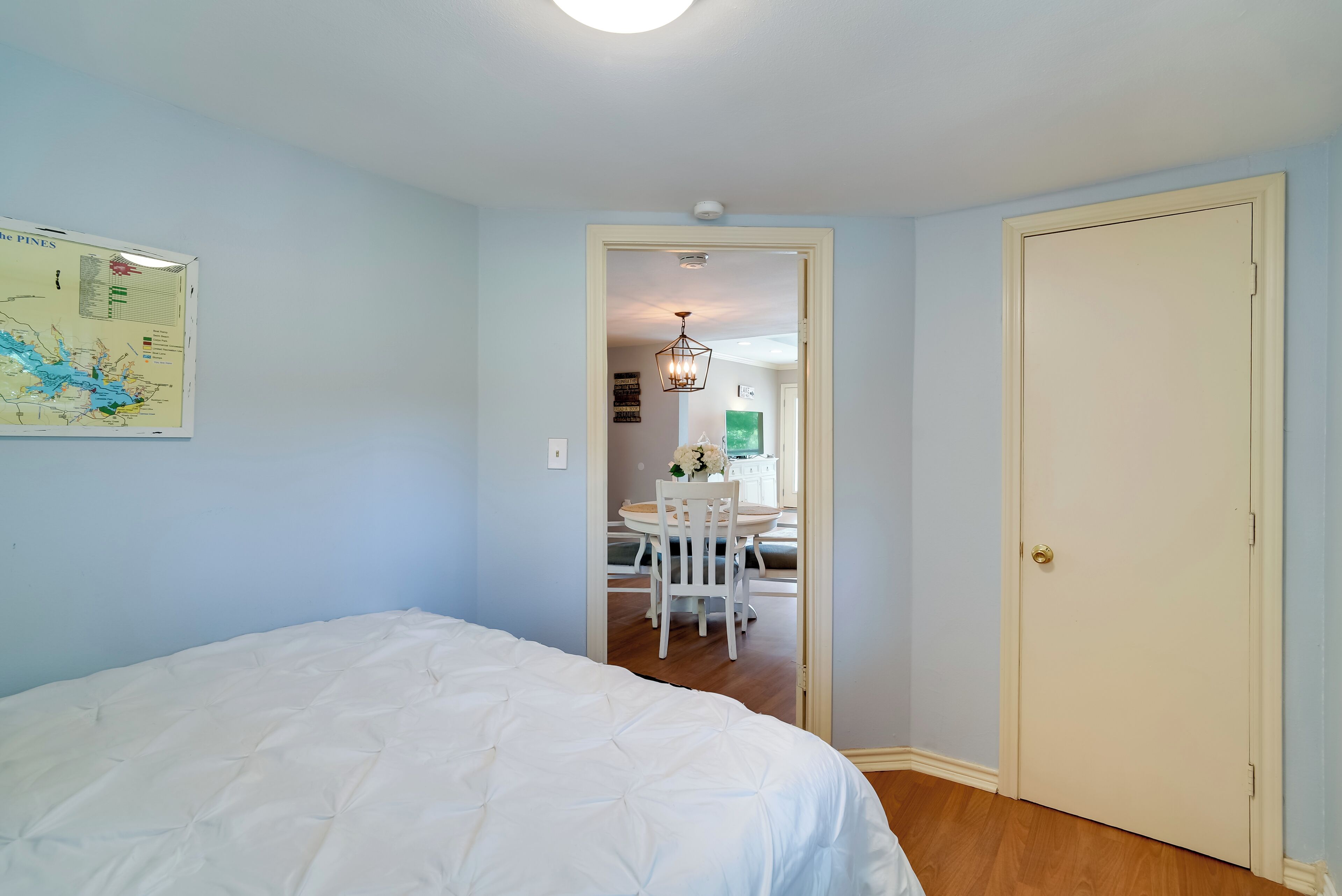 A bedroom with a bed, a map on the wall, and a door leading to a dining area.