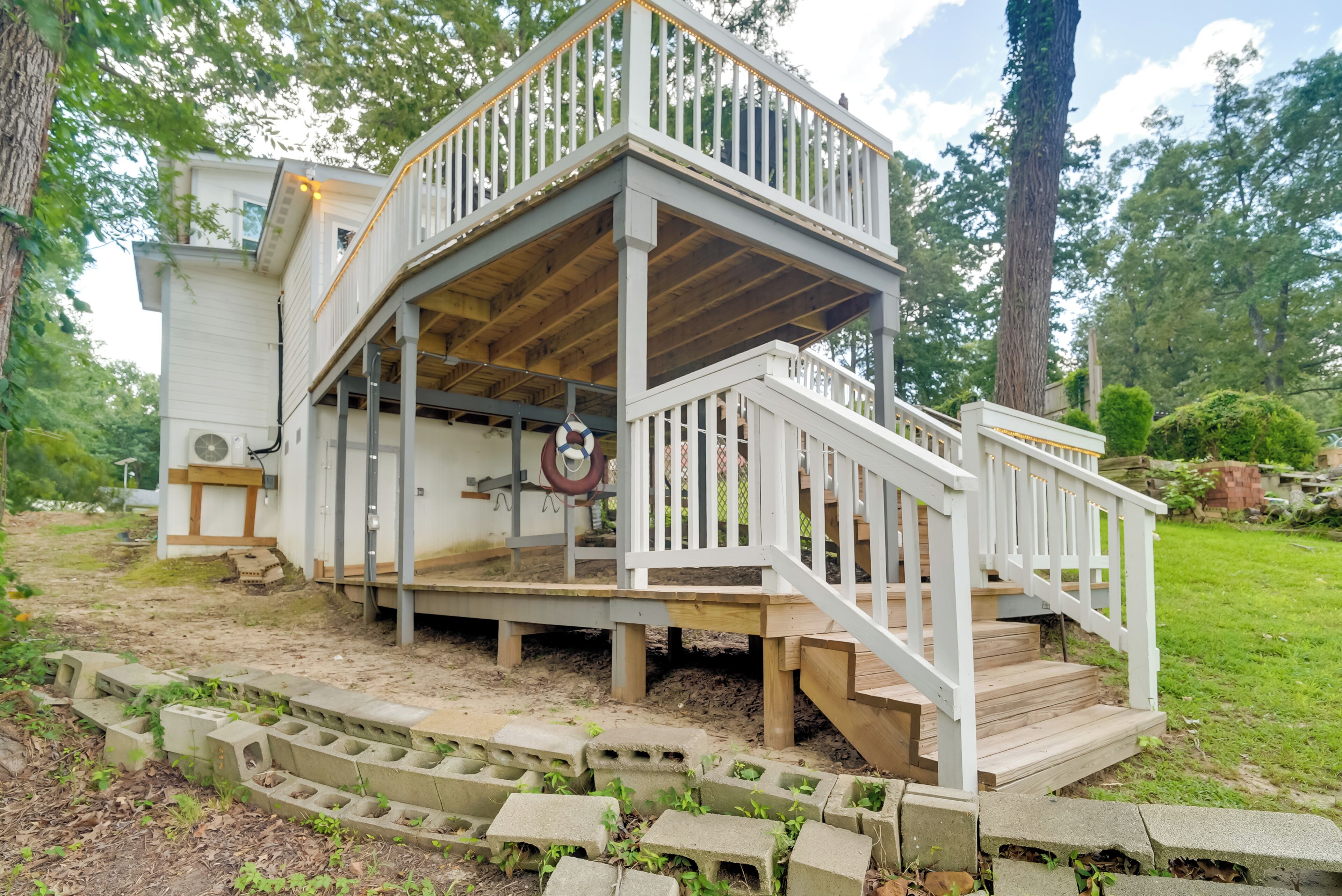 A two-story wooden deck with a white railing, surrounded by a landscaped garden.