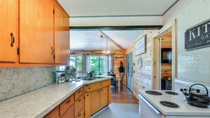 Une cuisine avec des meubles en bois, un poêle blanc et une pancarte sur laquelle on peut lire « JARDIN D’HERBES AROMATIQUES ».