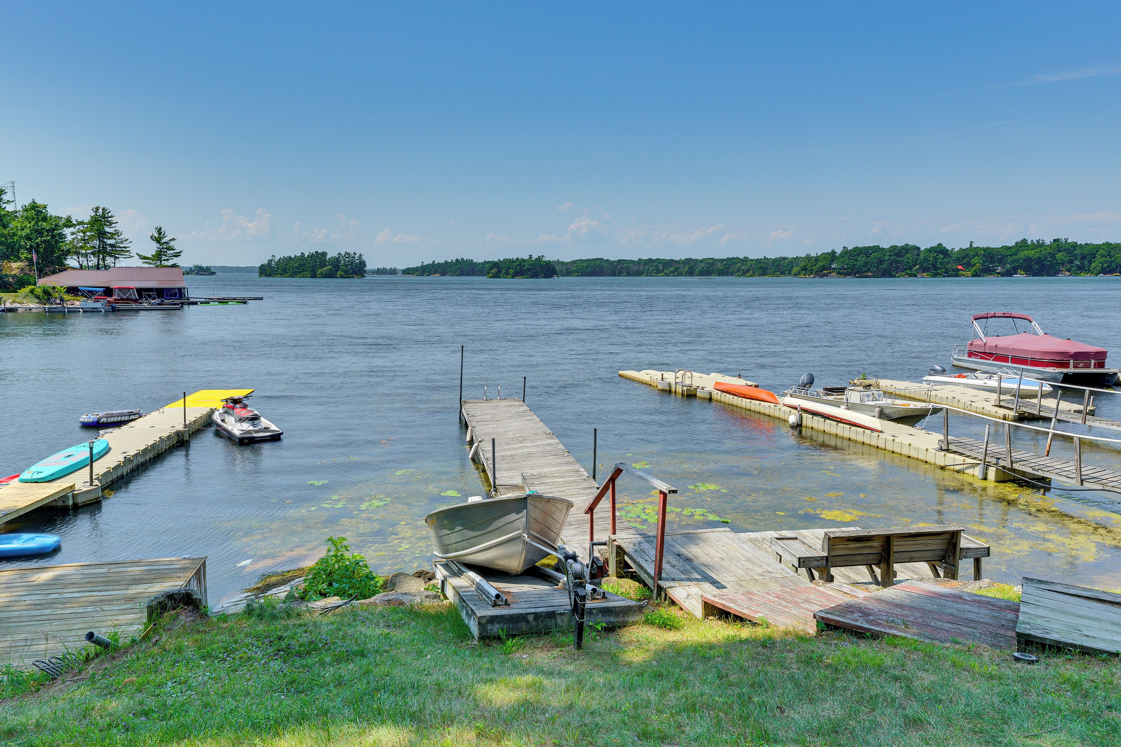 A lakeside dock with boats, a small docked boat, and a cabin in the background.