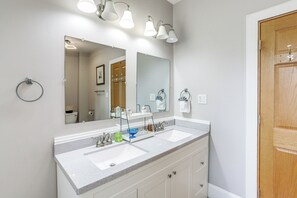 Une salle de bain avec deux lavabos, un grand miroir et une porte en bois.
