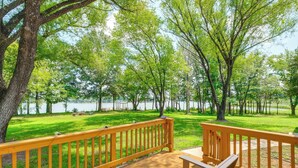 Eine Holzdar Terrasse mit Bänken mit Blick auf eine Wiese und einen See.