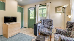 A living room with a television, a dresser, a chair, a lamp, and a door with curtains. - < 1/2 Mi to Osu: Studio in Corvallis Near Parks (Corvallis)